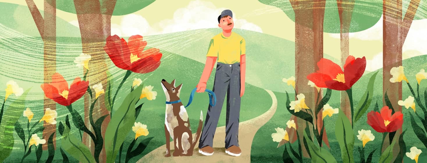 A man with a dog pauses on a nature path to look up into the trees and breathe in the air. Behind him are rolling hills and around him are large, bright flowers and grass.