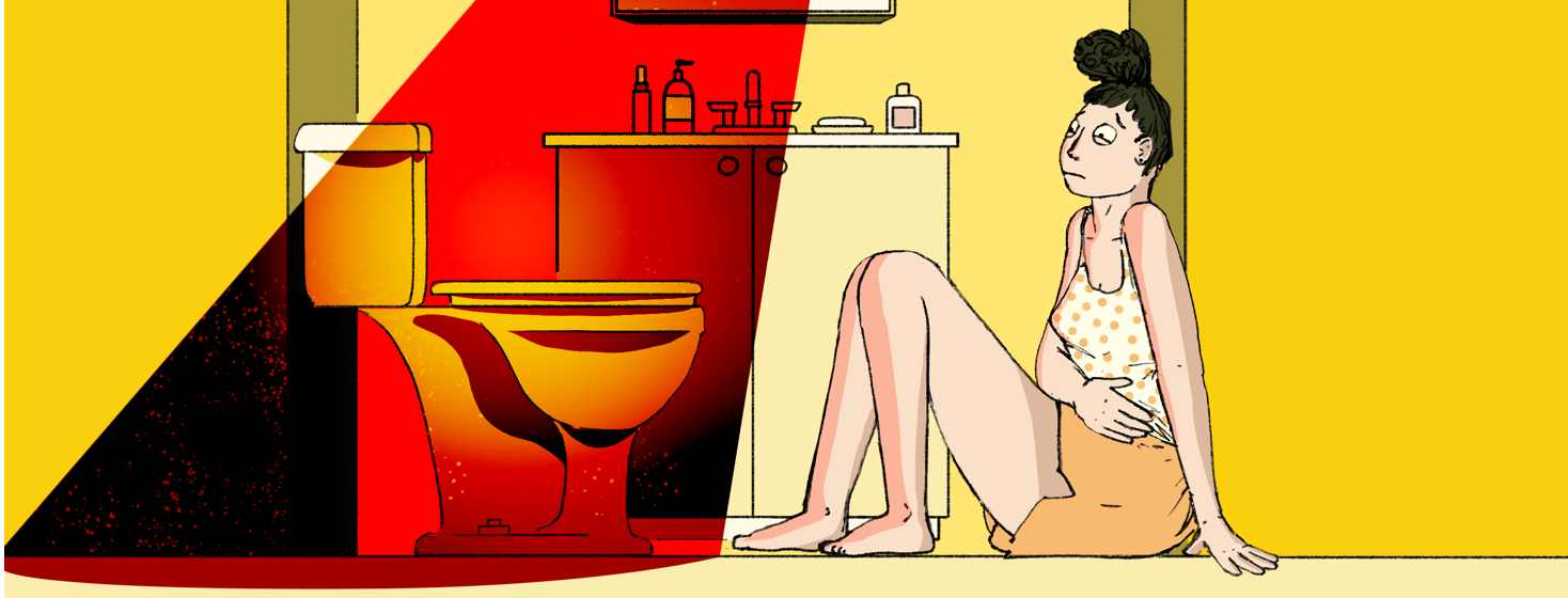 A woman sits on the bathroom floor, clutching her stomach in pain.